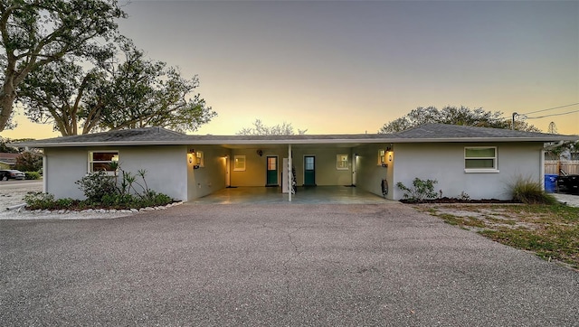 ranch-style house with driveway, an attached carport, and stucco siding