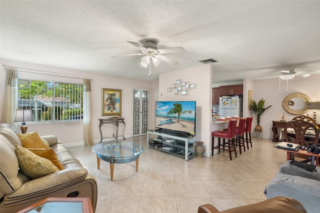 tiled living room with a textured ceiling and ceiling fan