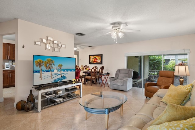 living room with light tile patterned flooring, ceiling fan, and a textured ceiling