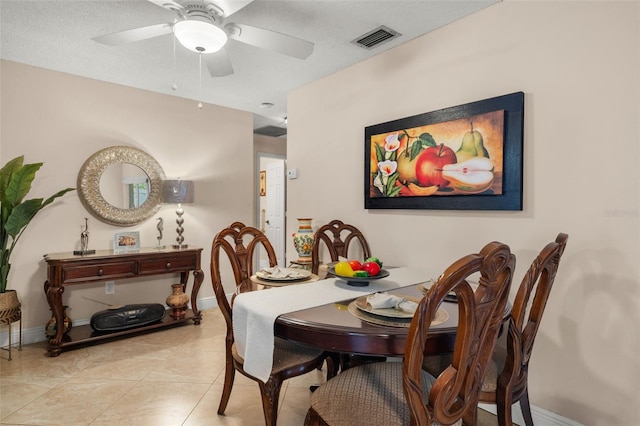 tiled dining room with a textured ceiling and ceiling fan