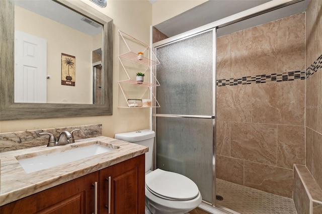 bathroom with vanity, toilet, and a shower with door