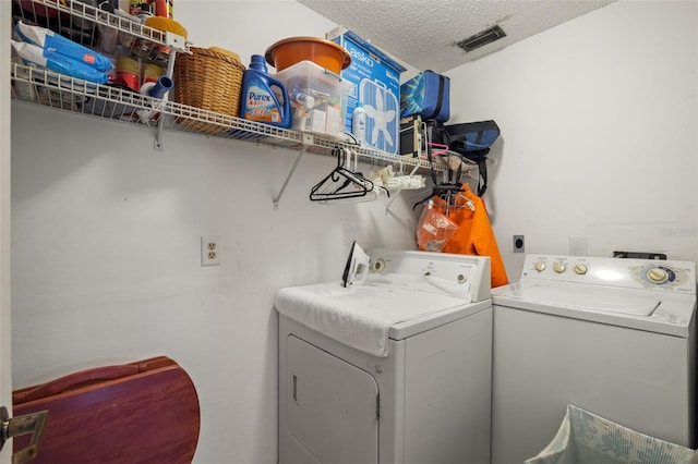 washroom with a textured ceiling and washing machine and clothes dryer