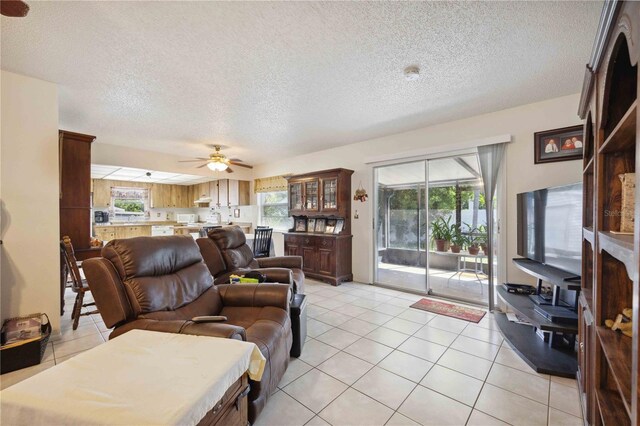 tiled living room featuring a healthy amount of sunlight, a textured ceiling, and ceiling fan