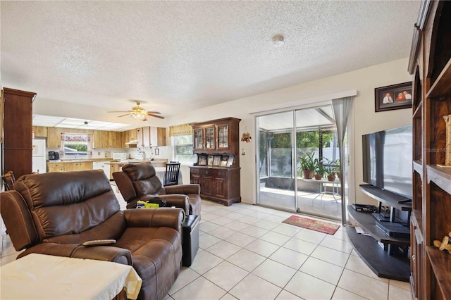 living room with ceiling fan, plenty of natural light, a textured ceiling, and light tile patterned floors