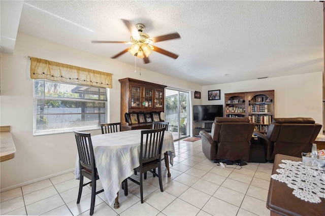 tiled dining space with ceiling fan and a textured ceiling