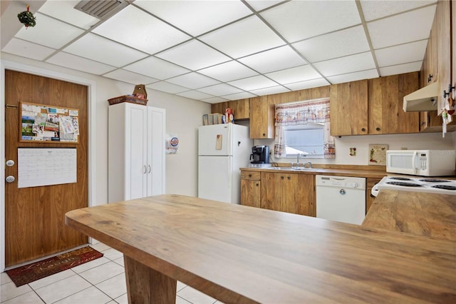 kitchen with white appliances, kitchen peninsula, sink, and light tile patterned floors