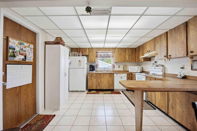 kitchen with white appliances, a paneled ceiling, sink, and light tile patterned floors