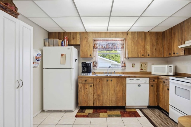 kitchen with sink, light tile patterned floors, a drop ceiling, and white appliances