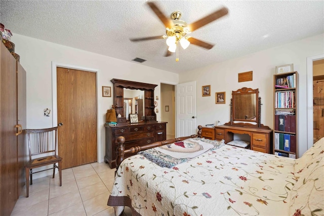 tiled bedroom with ceiling fan and a textured ceiling