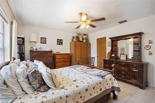 tiled bedroom with ceiling fan and a textured ceiling