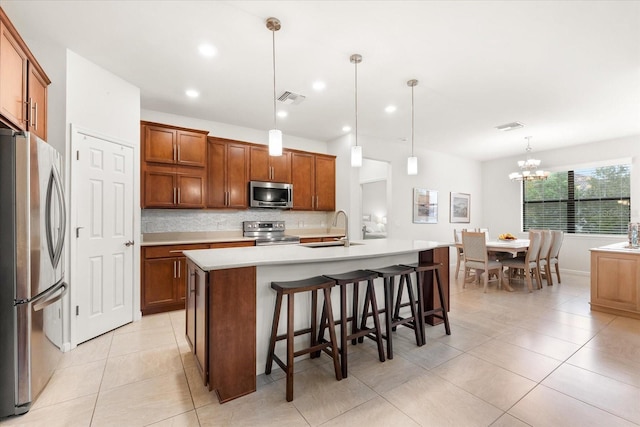 kitchen featuring sink, tasteful backsplash, decorative light fixtures, stainless steel appliances, and a kitchen island with sink