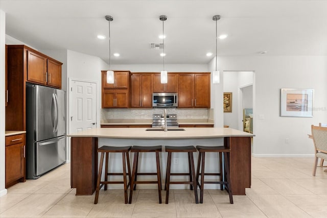 kitchen with stainless steel appliances, a center island with sink, and decorative light fixtures