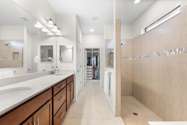 bathroom featuring vanity, tile patterned flooring, and a tile shower