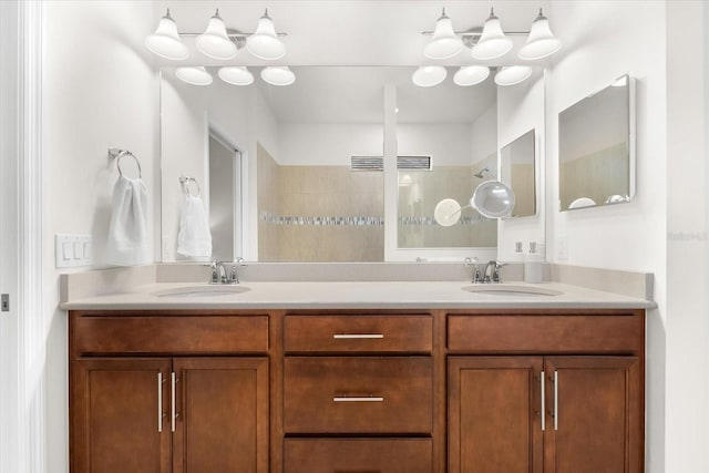 bathroom featuring tiled shower and vanity