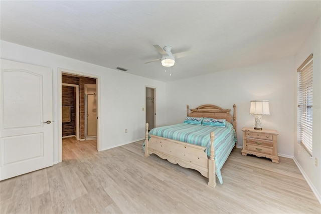 bedroom with ceiling fan, a walk in closet, and light wood-type flooring