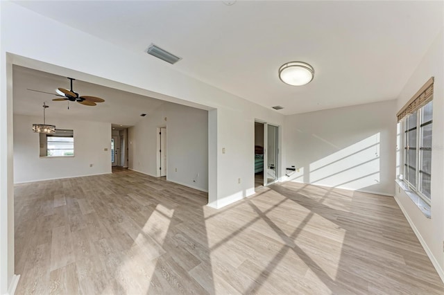 unfurnished living room featuring ceiling fan with notable chandelier and light hardwood / wood-style floors