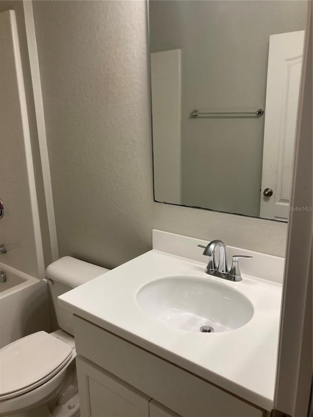 bathroom with a textured wall, vanity, toilet, and shower / bathtub combination