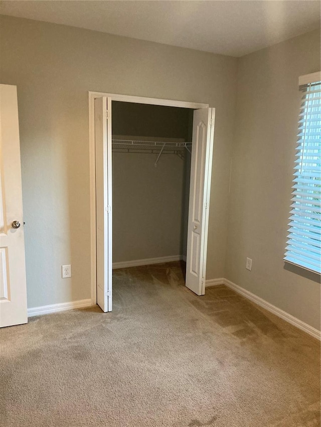 unfurnished bedroom featuring light carpet and a closet