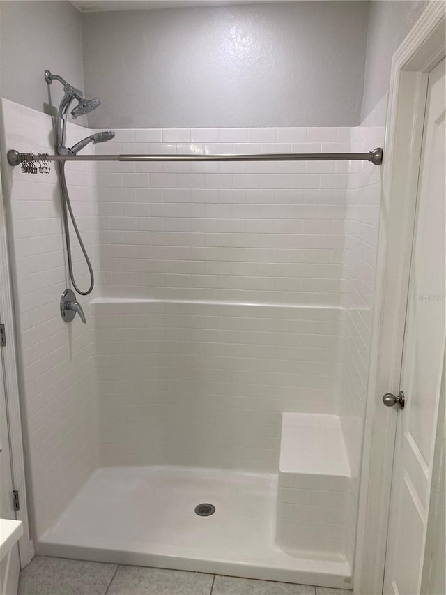 bathroom with a tile shower and tile patterned floors