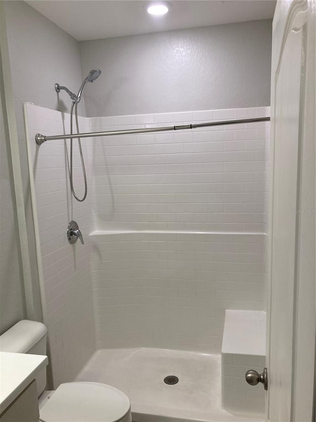 bathroom featuring tiled shower, vanity, and toilet