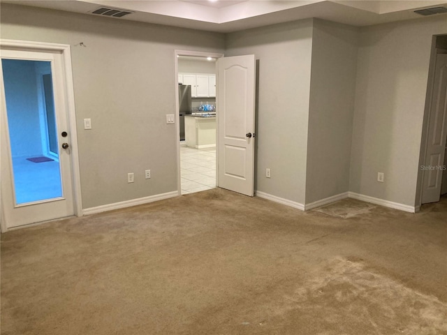 unfurnished room with baseboards, visible vents, and light colored carpet