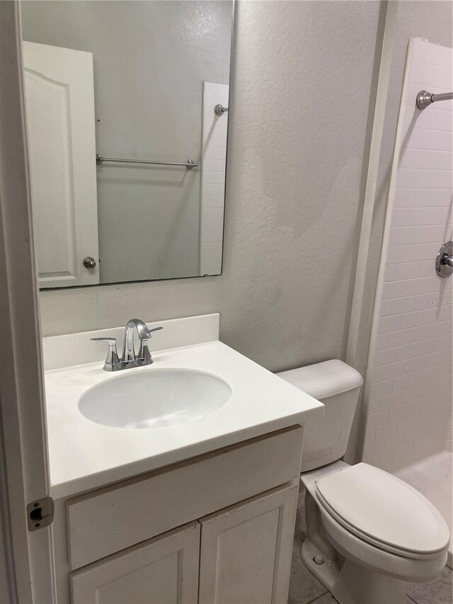 full bathroom with a stall shower, a textured wall, vanity, and toilet