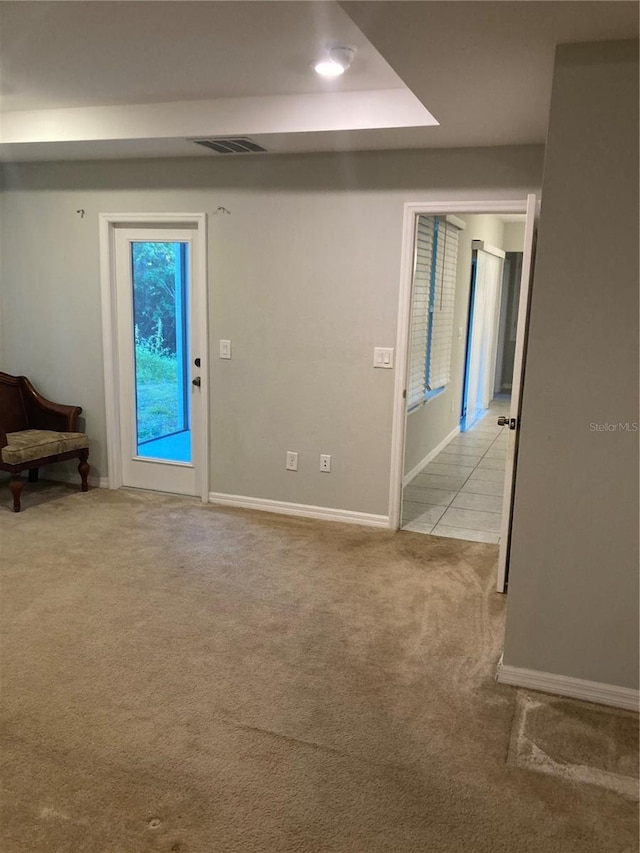 interior space with baseboards, visible vents, and light colored carpet