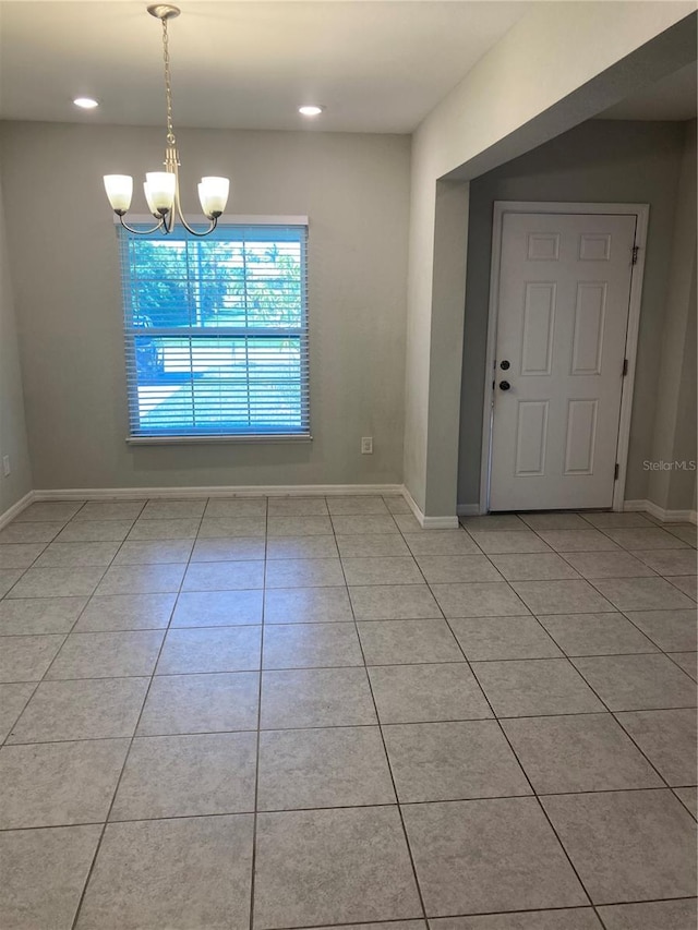 unfurnished dining area with light tile patterned floors, baseboards, and a notable chandelier