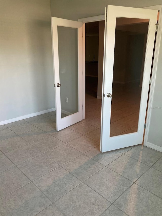 spare room featuring light tile patterned floors, baseboards, and french doors