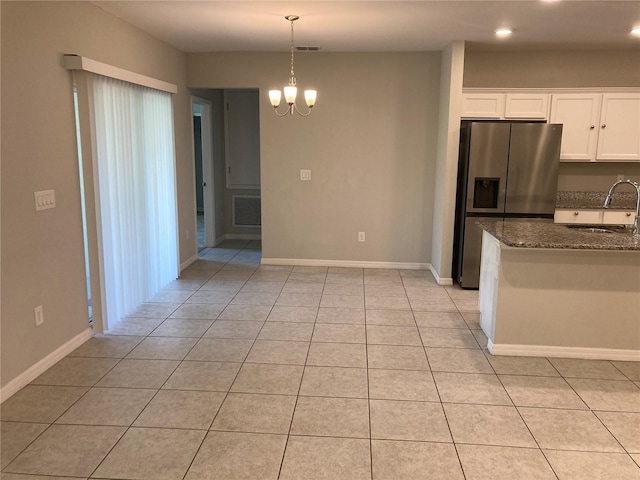 kitchen featuring dark stone counters, white cabinets, a sink, stainless steel refrigerator with ice dispenser, and a notable chandelier