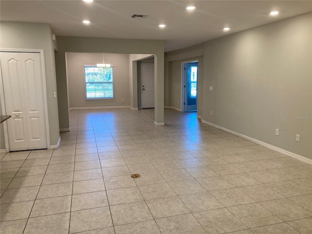 empty room featuring a notable chandelier, light tile patterned floors, recessed lighting, visible vents, and baseboards