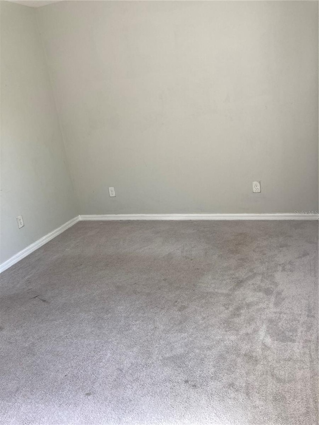 carpeted empty room featuring baseboards