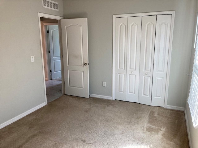 unfurnished bedroom featuring light colored carpet, a closet, visible vents, and baseboards