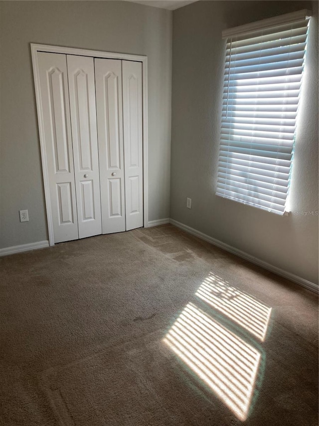 unfurnished bedroom featuring carpet, a closet, and baseboards