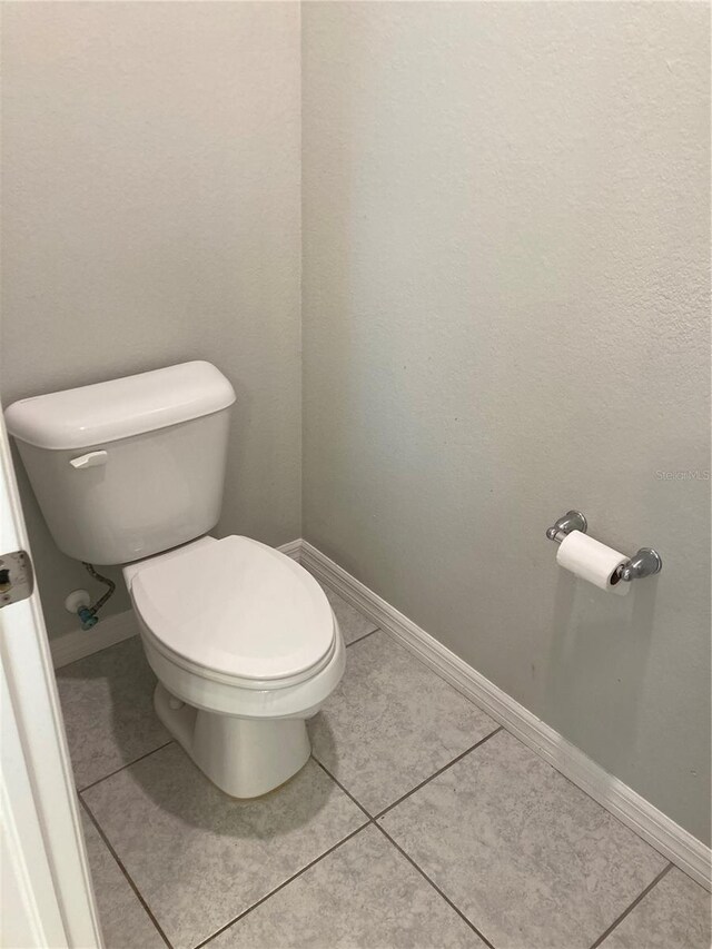 bathroom featuring toilet, tile patterned flooring, and baseboards