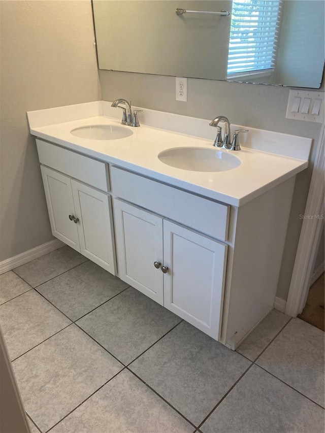 full bath featuring double vanity, tile patterned flooring, baseboards, and a sink