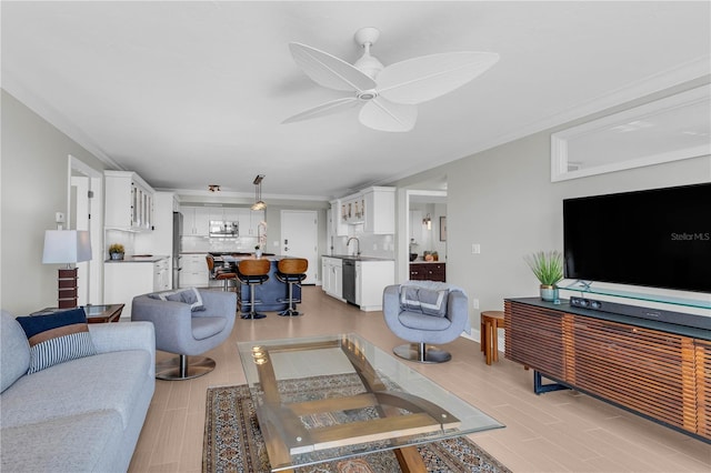 living room with ceiling fan, ornamental molding, sink, and light hardwood / wood-style flooring