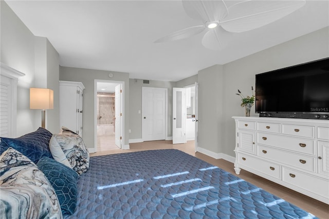 bedroom with ensuite bath, ceiling fan, and hardwood / wood-style flooring