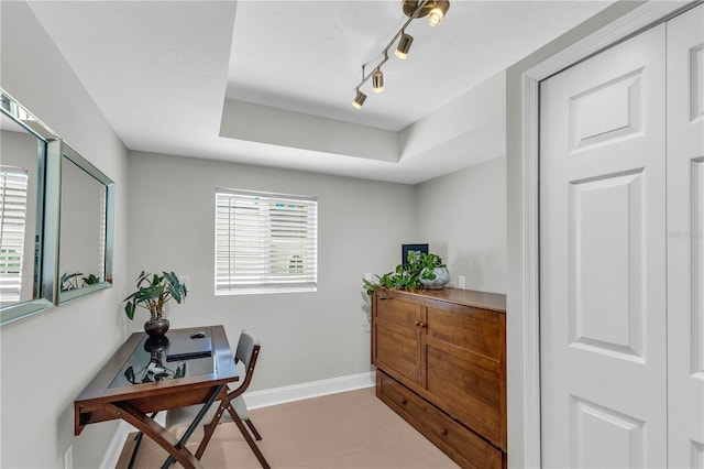 home office with rail lighting and a tray ceiling