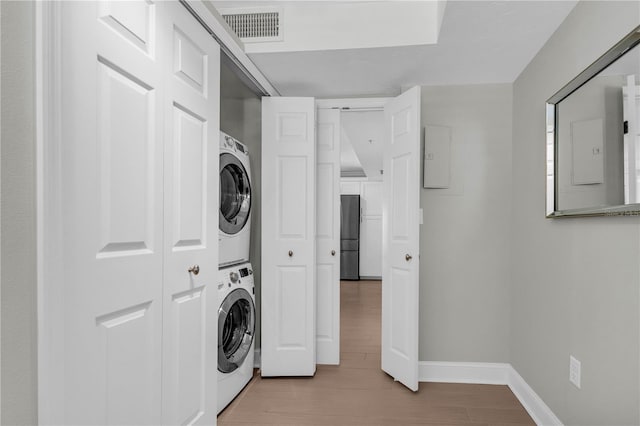 laundry area featuring stacked washer / drying machine and light hardwood / wood-style floors