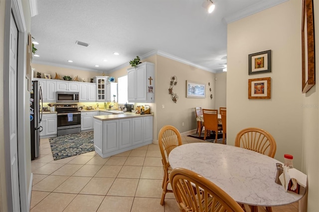 kitchen featuring light tile patterned floors, crown molding, white cabinets, and appliances with stainless steel finishes