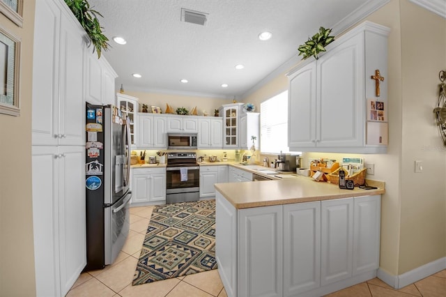 kitchen featuring white cabinetry, a textured ceiling, light tile patterned floors, appliances with stainless steel finishes, and kitchen peninsula