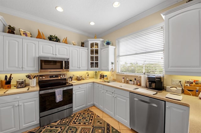 kitchen featuring white cabinetry, light tile patterned flooring, ornamental molding, and appliances with stainless steel finishes