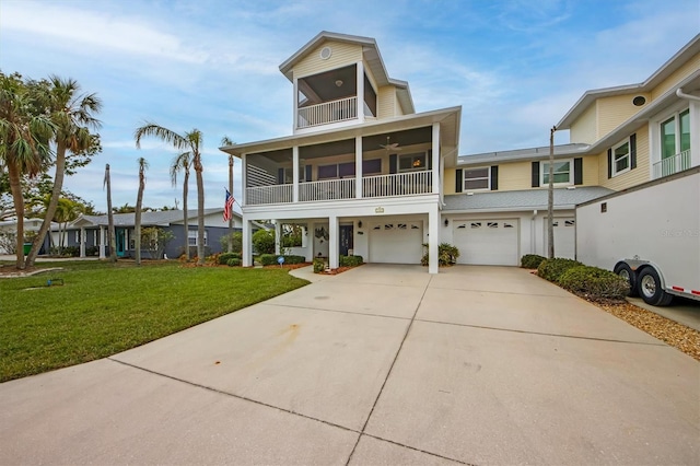 view of front facade with a garage, a balcony, a front yard, and a sunroom