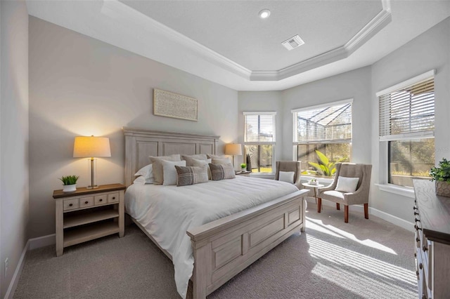 carpeted bedroom featuring multiple windows, ornamental molding, and a tray ceiling