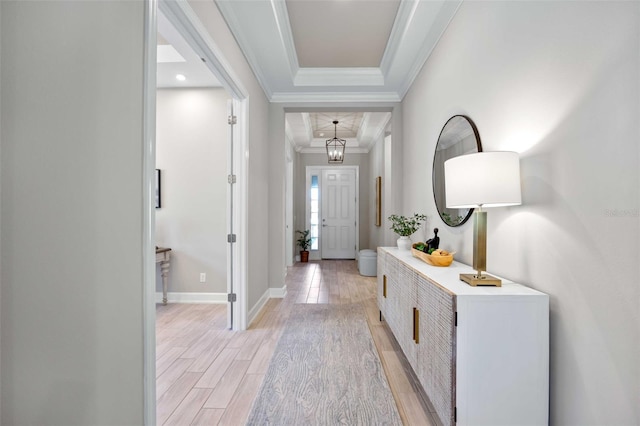 foyer entrance featuring crown molding, a tray ceiling, and light wood-type flooring