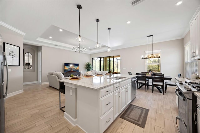 kitchen with stainless steel appliances, a chandelier, an island with sink, and white cabinets