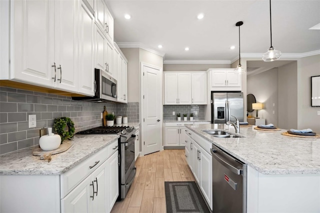 kitchen featuring sink, stainless steel appliances, an island with sink, white cabinets, and decorative light fixtures