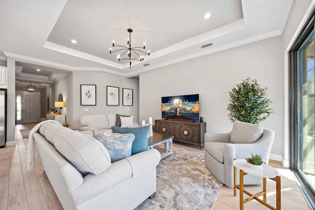 living room with a healthy amount of sunlight, an inviting chandelier, and a tray ceiling