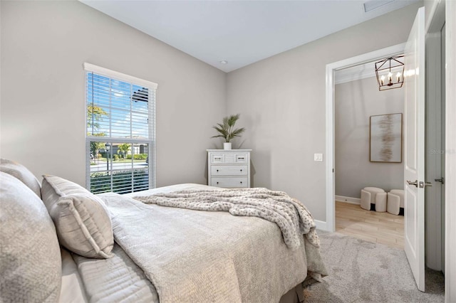 bedroom with light hardwood / wood-style flooring and a notable chandelier